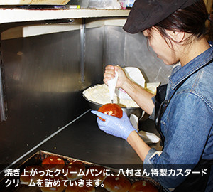 焼き上がったクリームパンに、八村さん特製カスタードクリームを詰めていきます。